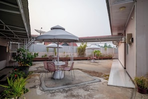 An outdoor patio area with tables and chairs, umbrellas, and potted plants.