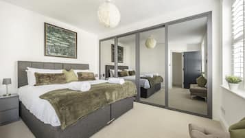 A modern bedroom with a large bed, a mirror, and a view of a balcony.