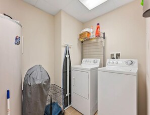 A laundry room with two washing machines, a drying rack, and a covered storage area. - Residence 709 at The Grand (Wildwood)