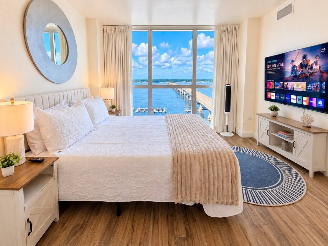 Ein Hotelzimmer mit einem großen Bett, einem Fernseher, Meerblick und Holzboden.