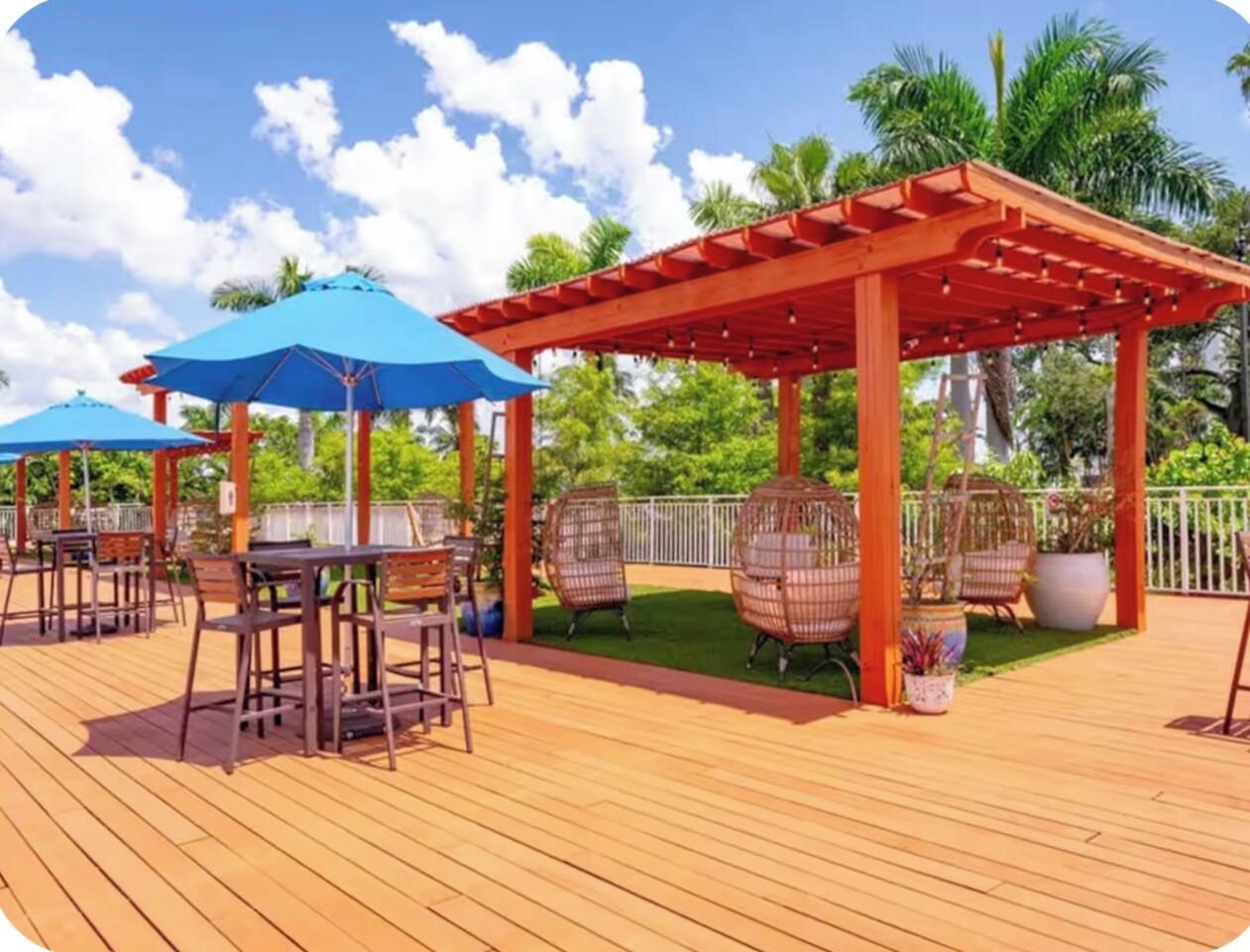 Eine Holzterrasse mit Außenmöbeln, darunter Tische und Stühle, sowie eine Pergola.