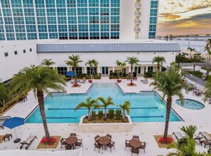 Ein Hotel mit einem großen Pool, umgeben von Palmen und Liegestühlen.