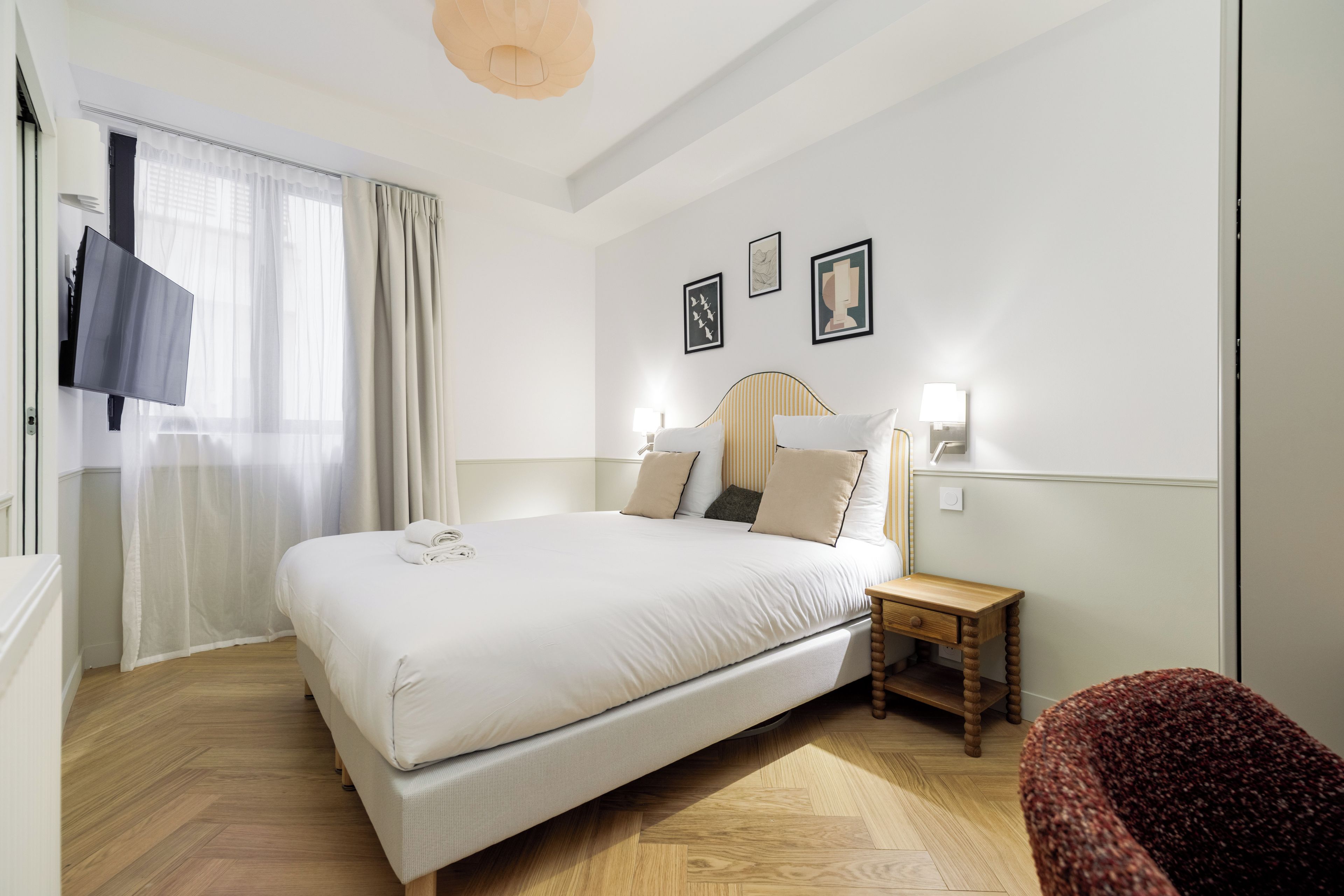 Una habitación de hotel con una cama grande, una mesita de noche, una silla y una obra de arte en la pared.