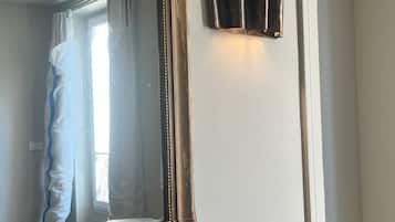 Ein Zimmer mit einem großen Spiegel, einer Wandleuchte und einem Marmor-Kamin.
