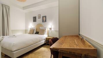 Una habitación de hotel con cama, mesitas de noche, un escritorio de madera y una silla.