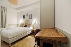 A hotel room with a bed, bedside tables, a wooden desk, and a chair. - Faubourg (Paris)