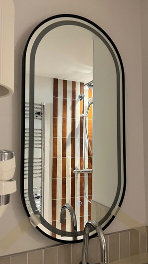 A bathroom with a mirror, a shower, and a sink. - Faubourg (Paris)