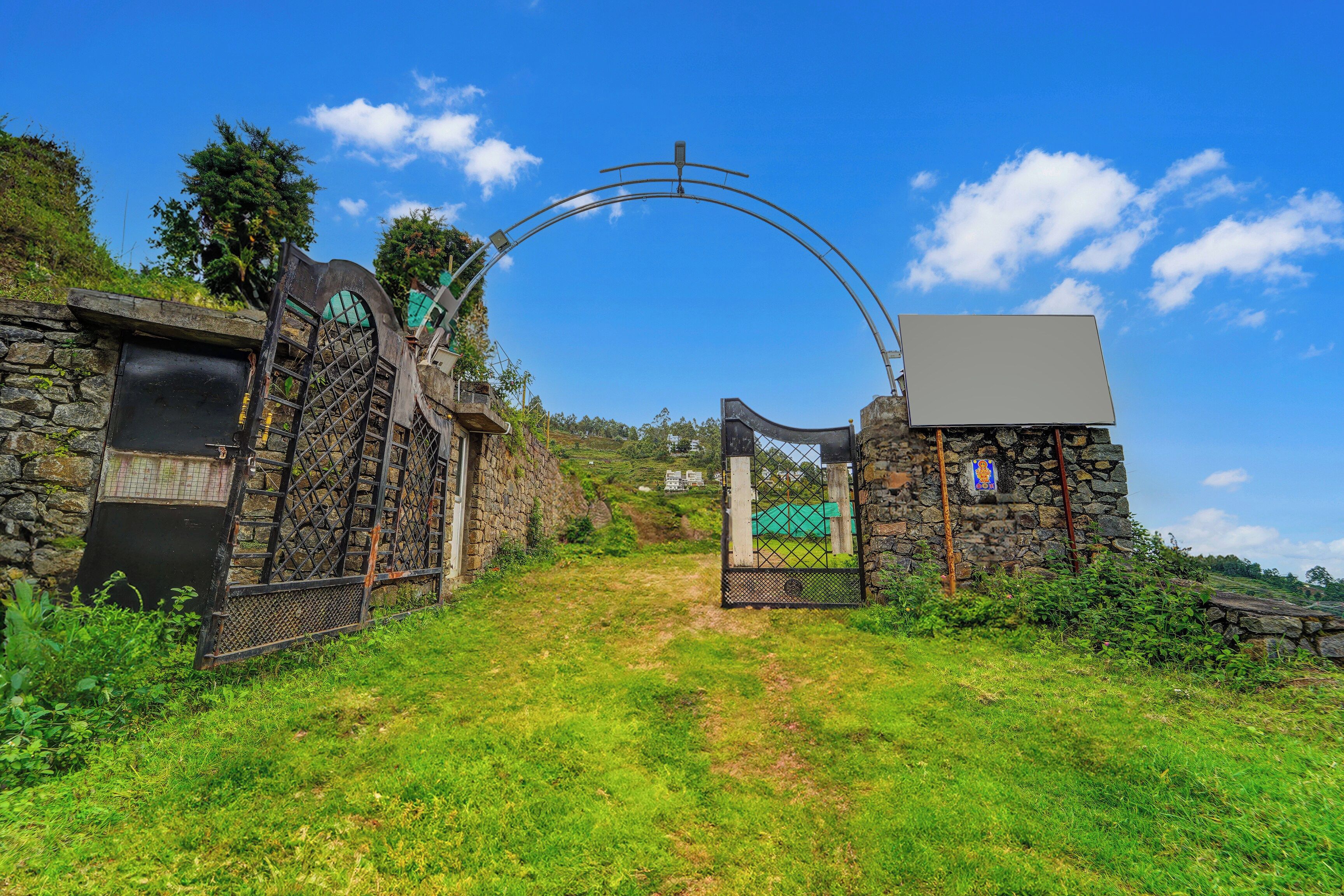 A stone gate with a metal archway leading to a grassy path.