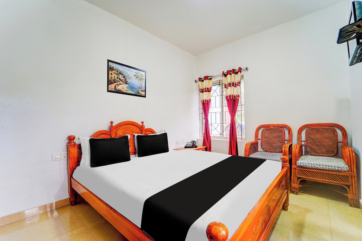 A hotel room with a bed, a chair, a window with curtains, and a painting on the wall.