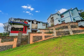 A hotel with a prominent 'HOTELO' sign, a staircase leading to the entrance, and a view of the surrounding landscape. - Hotel O Kodaikanal Vilpatti (Kodaikanal)