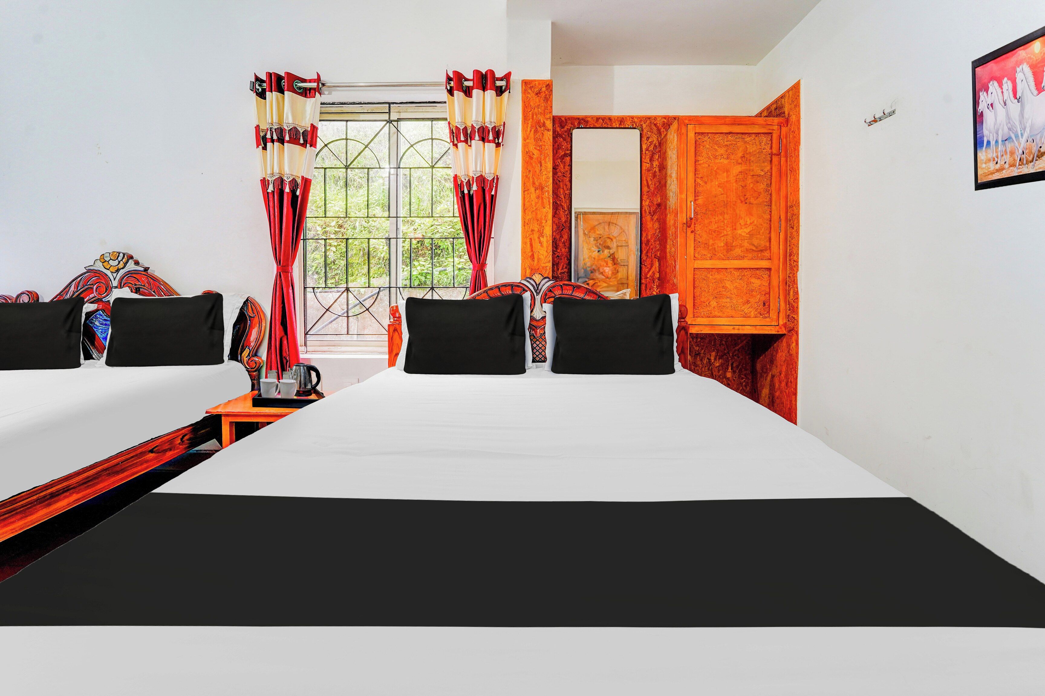 A hotel room with a bed, two bedside tables, a window with curtains, a wooden door, and a painting on the wall.
