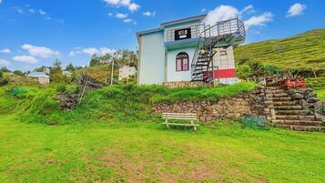 A hotel with a staircase leading to the entrance, surrounded by lush greenery.