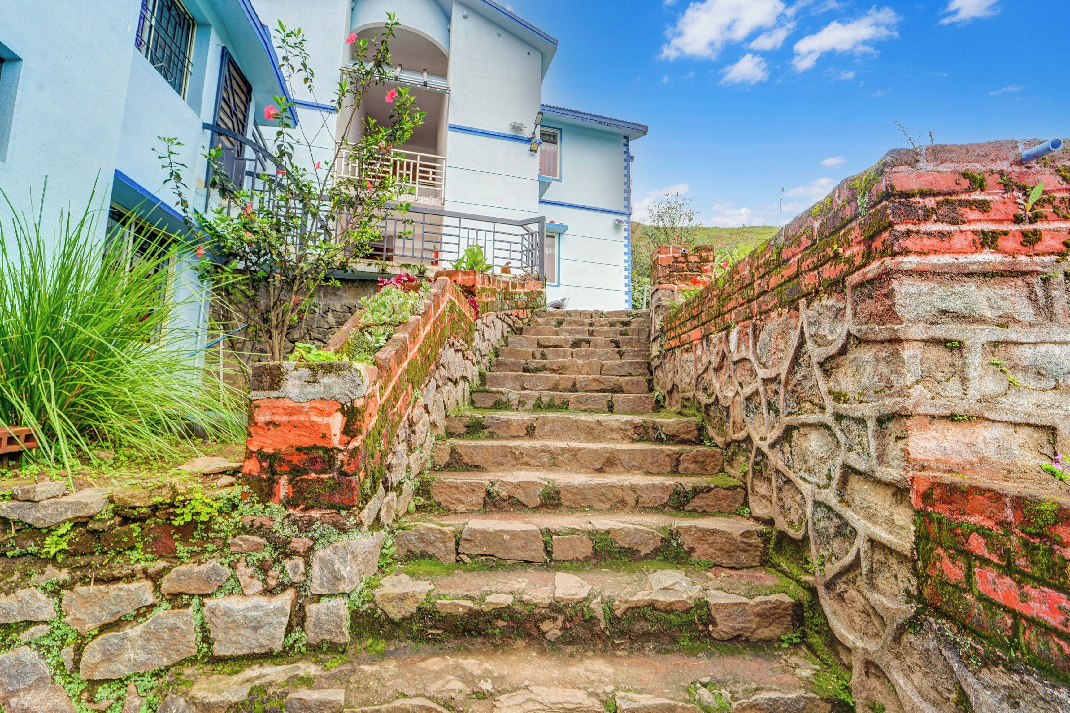 A stone staircase leading to a white building with blue trim and a balcony.