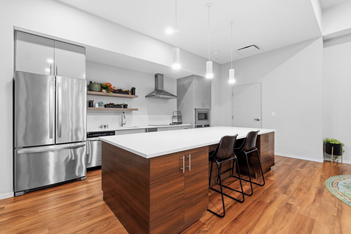 Een moderne keuken met een centraal eiland, roestvrijstalen apparatuur en hanglampen.