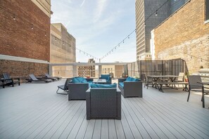 Un espacio al aire libre con mobiliario de mimbre y una parrilla.