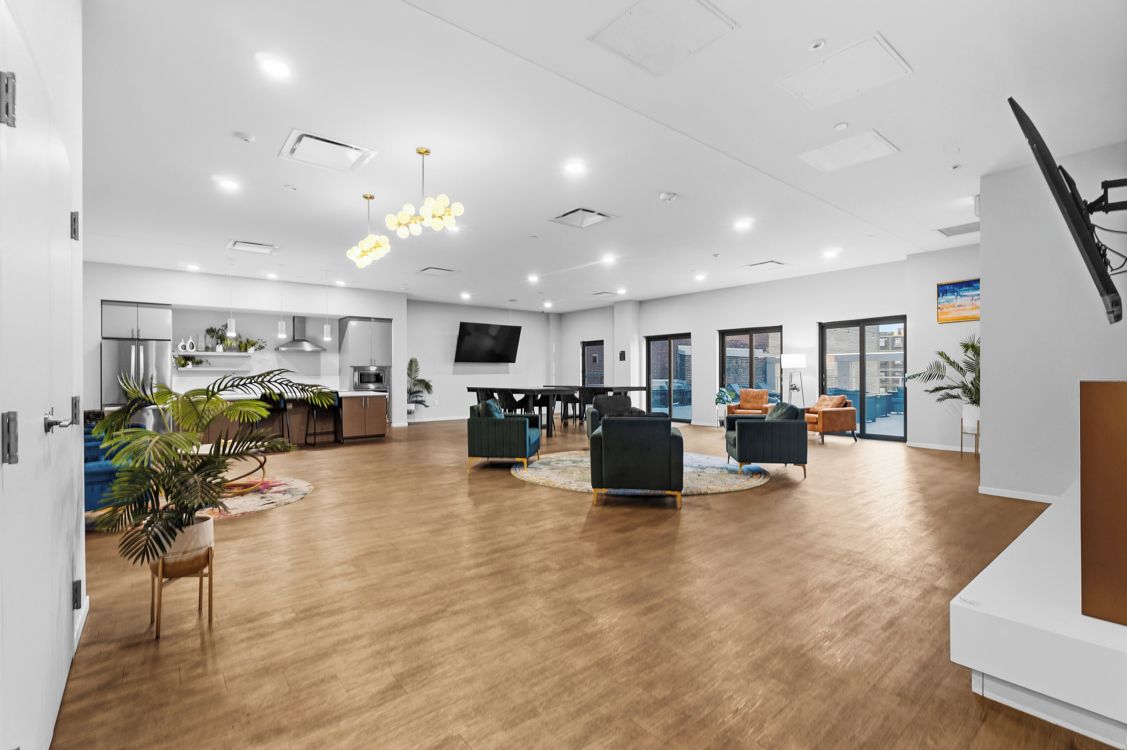 A spacious living area with a dining table, sofas, and a TV.