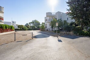 A residential building with a gated entrance, a clear sky, and surrounding greenery. - GuestHost - Seaside Bright Apartment with balcony (Bari)