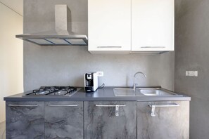 A modern kitchen with a gas stove, coffee maker, and a sink. - GuestHost - Seaside Bright Apartment with balcony (Bari)