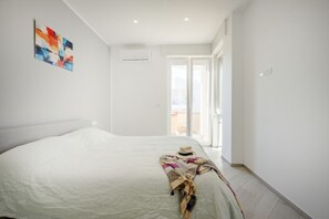 Une chambre à coucher avec un lit, une fenêtre et une porte donnant sur un espace extérieur.