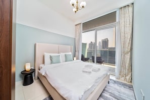 A hotel room with a large bed, a nightstand, a lamp, and a view of the city through a large window. - 1 BR Burj Khalifa View at Vera (Dubai)