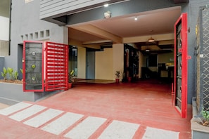 A building entrance with a red gate, a tiled floor, and a potted plant. - Hotel O Whitefield (Bangalore)