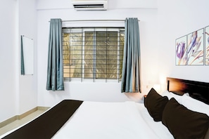 A hotel room with a bed, a window with curtains, a wall-mounted air conditioner, and a framed artwork. - Hotel O Whitefield (Bangalore)