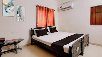 Un dormitorio ordenado con una cama, una mesita de noche y un aire acondicionado instalado en la pared.