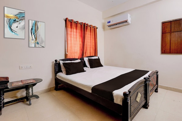 A neatly arranged bedroom with a bed, a bedside table, and a wall-mounted air conditioner. - Hotel O Enikepadu (Penumuluru)