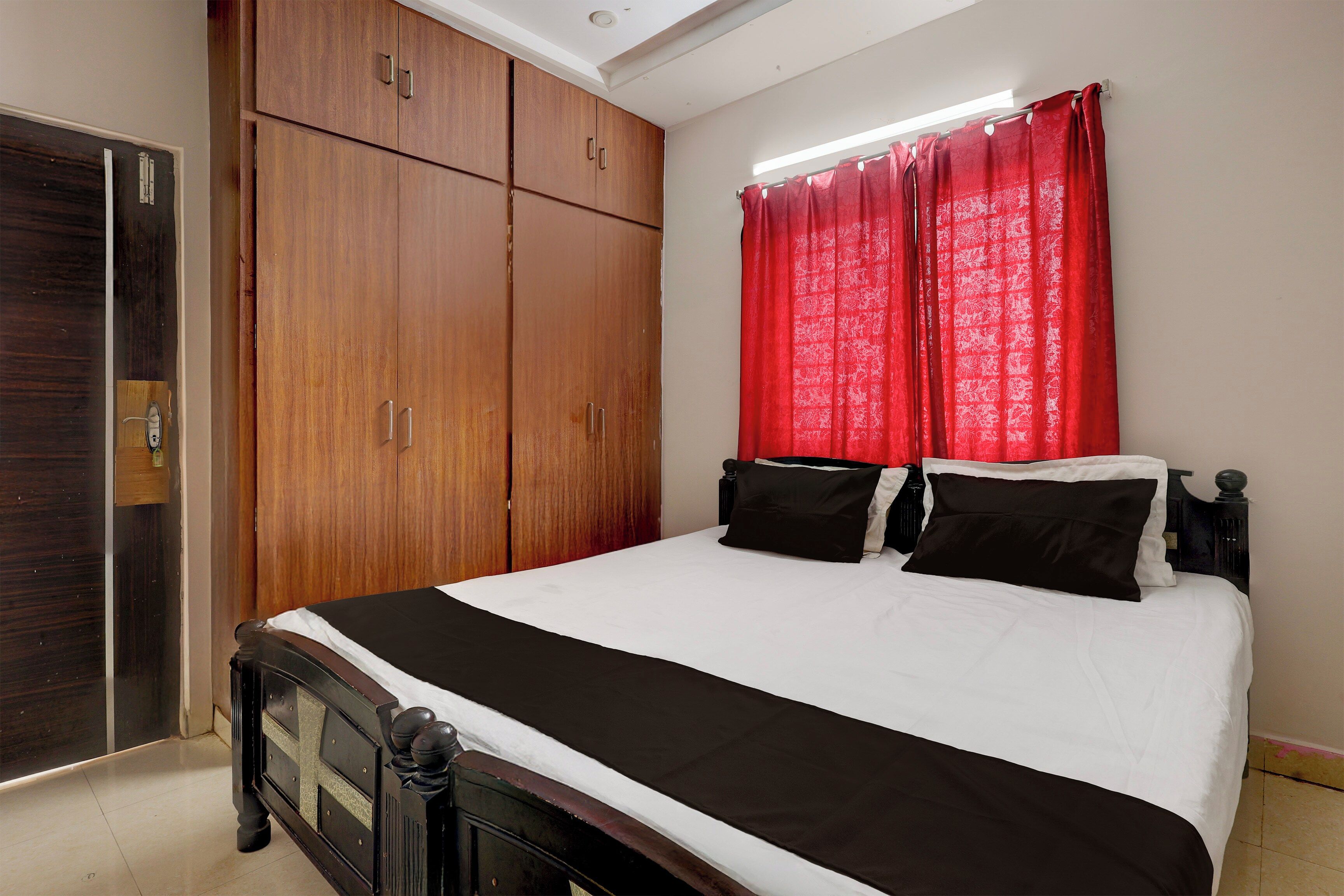 Een slaapkamer met een bed, een kledingkast en een raam met gordijnen.