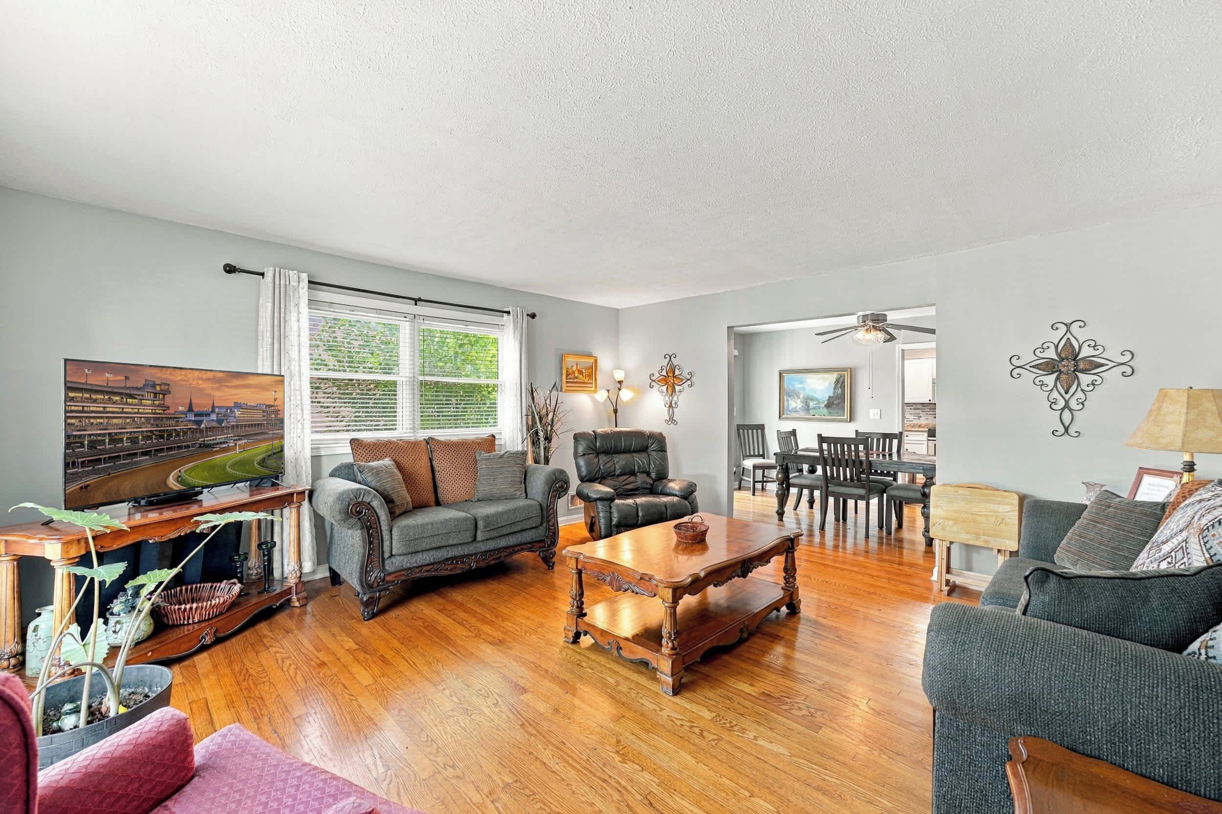 A spacious living room with a large flat-screen TV, a fireplace, and a dining area with a chandelier.