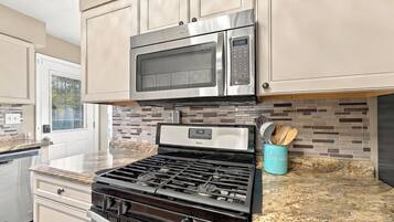 A kitchen with stainless steel appliances, a tiled backsplash, and a granite countertop.