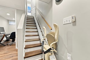 A staircase with a handrail, a chair, and a wall-mounted electrical outlet. - Spacious home near Bourbon Trail & Churchill Downs (Louisville)