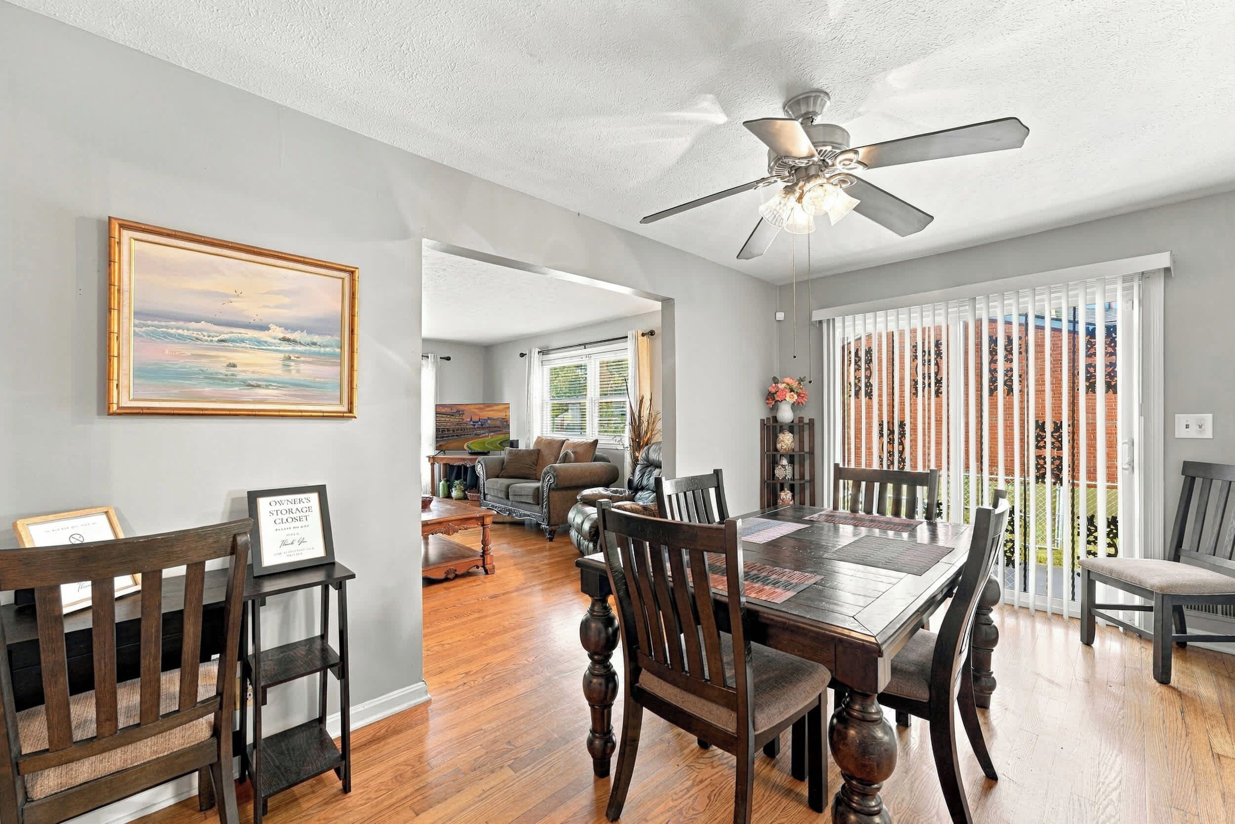 A dining area with a wooden table, chairs, and a ceiling fan.