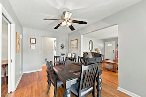 A dining area with a wooden table and chairs, a ceiling fan, and a view into the living room. - Spacious home near Bourbon Trail & Churchill Downs (Louisville)