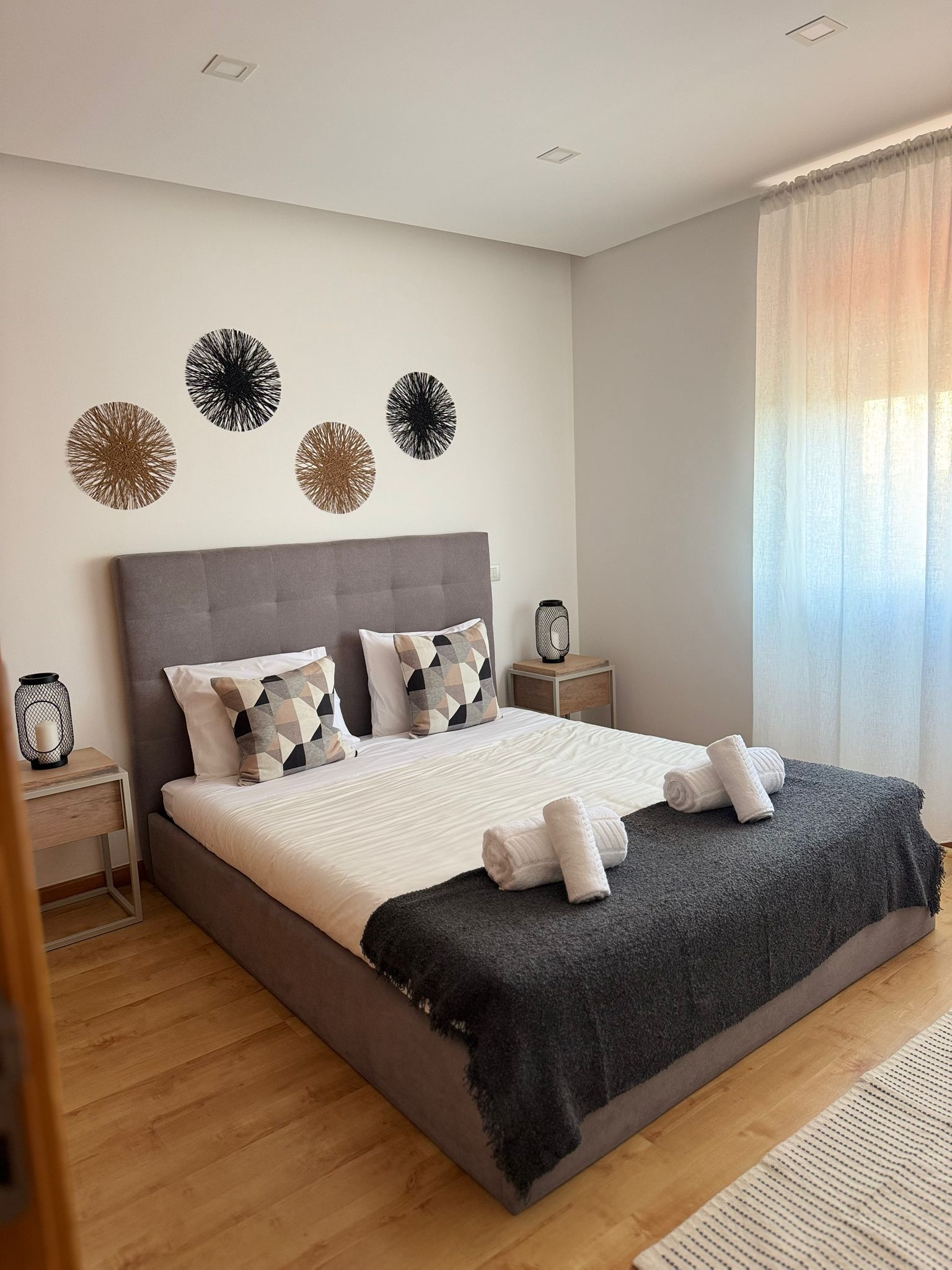 A modern bedroom with a large bed, a grey headboard, and decorative wall art.