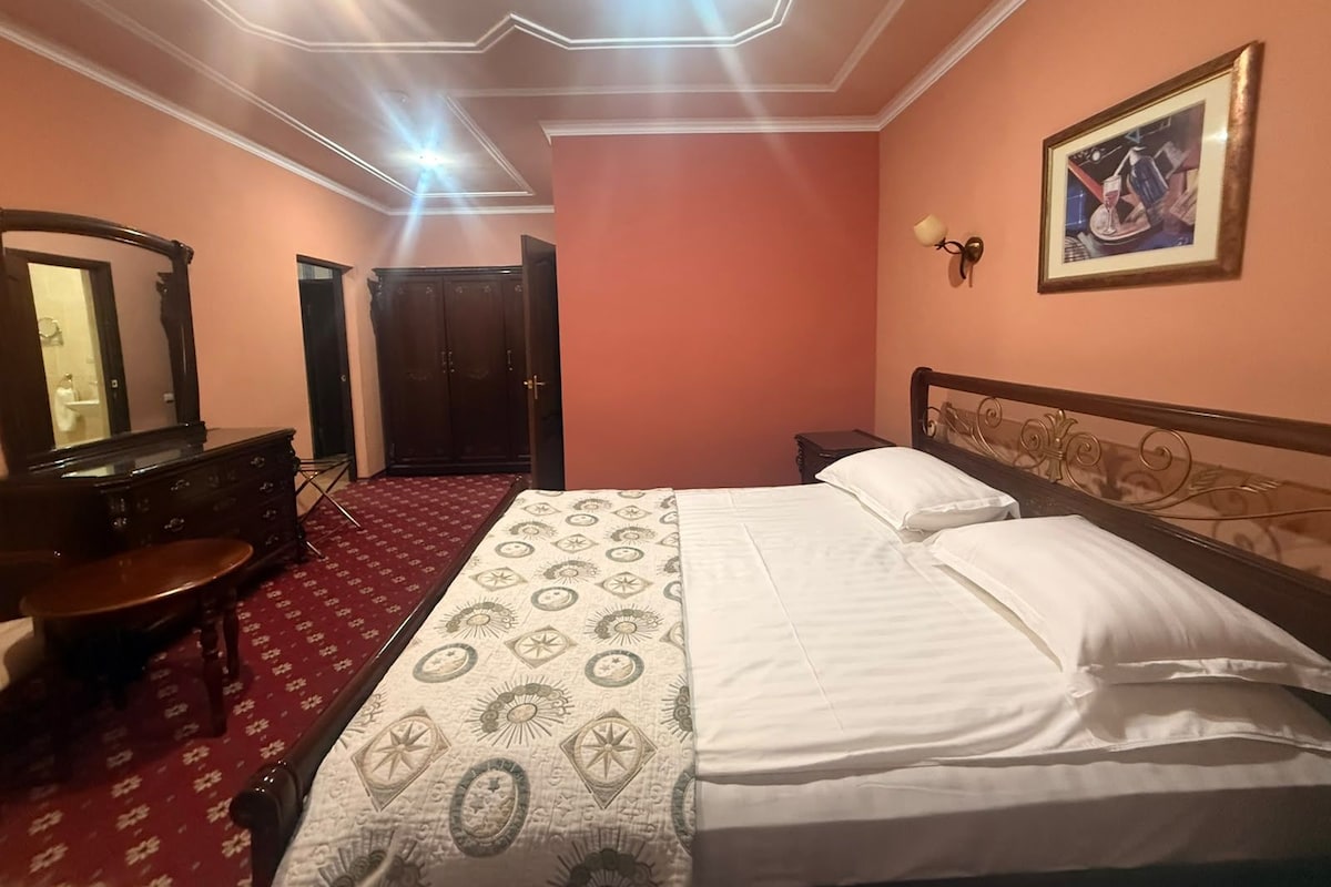 Een hotelkamer met een bed, een dressoir, een spiegel, een kledingkast en een schilderij aan de muur.