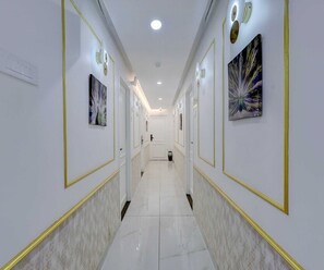 A hallway with white walls, gold trim, and artwork.