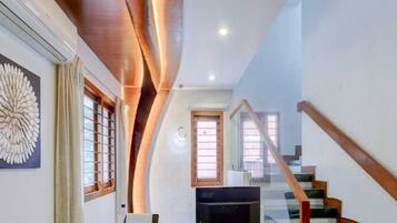 A modern living room with a flat-screen TV, a printer, and a staircase leading to an upper level.