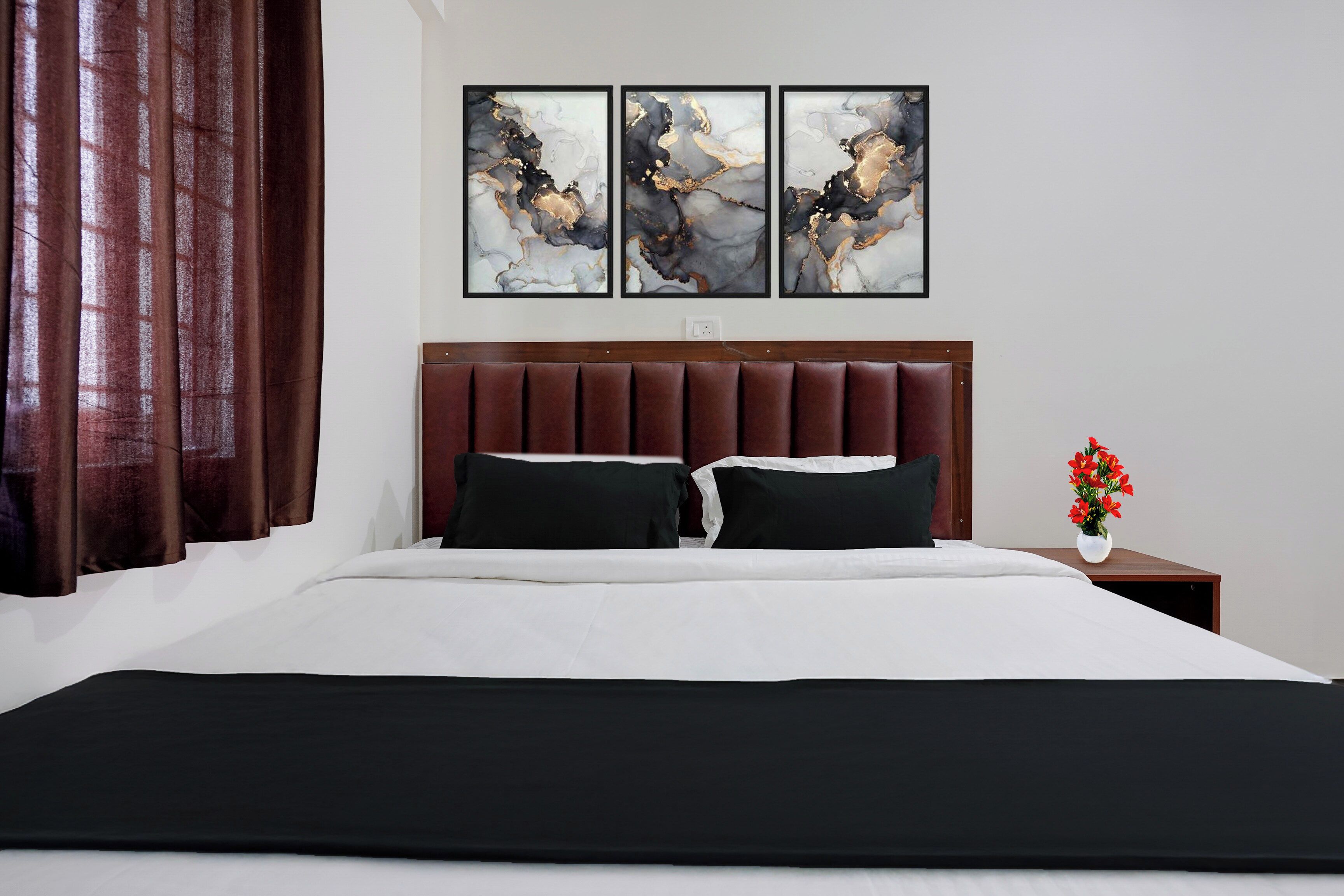 Una camera d'albergo con un letto grande, una testiera in legno e tre quadri astratti appesi al muro.