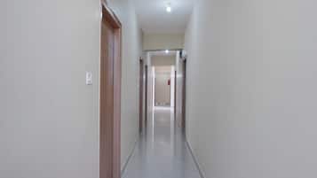 A narrow, well-lit hallway with a tiled floor, leading to a door at the end.