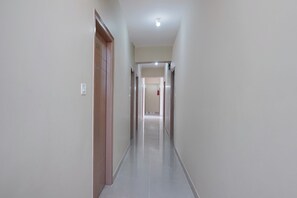 Un pasillo estrecho y bien iluminado con piso de baldosas, que conduce a una puerta al final.