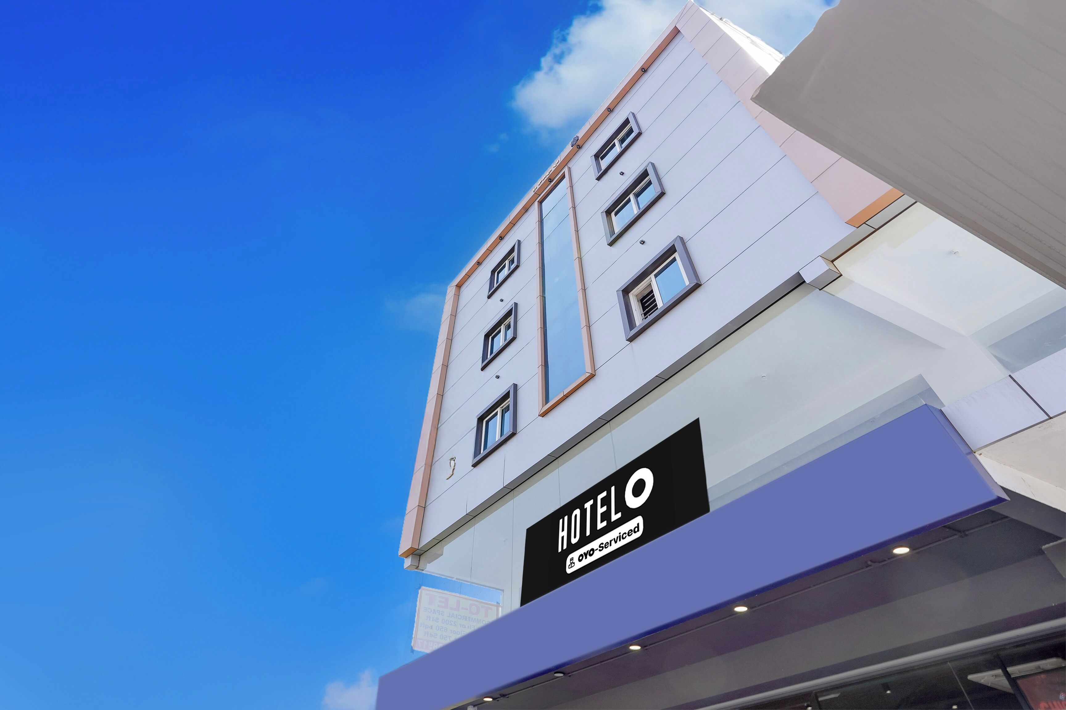 En hotellbyggnad med många fönster och en skylt som visar att det är ett OYO Service-hotell.