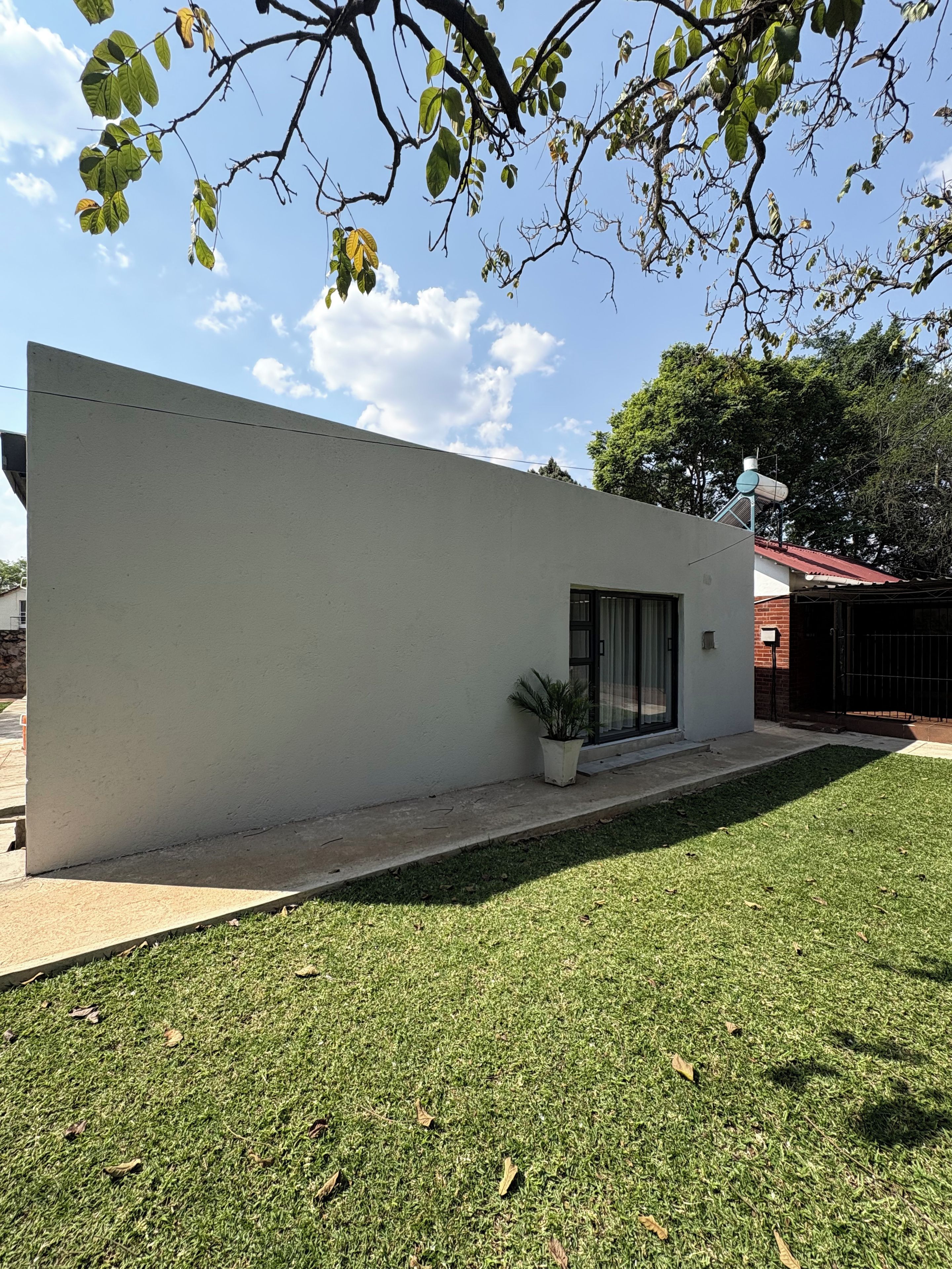 A modern building with a flat roof, a small potted plant, and a clear sky.