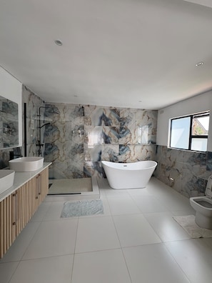 Un bagno moderno con una vasca da bagno indipendente, due lavabi e un box doccia in vetro.