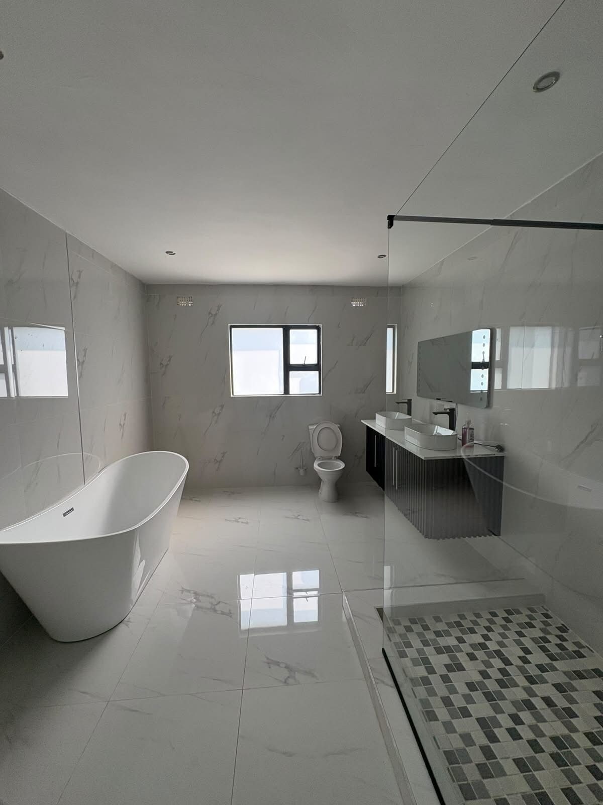 A modern bathroom with a freestanding bathtub, a toilet, a sink, and a shower area.
