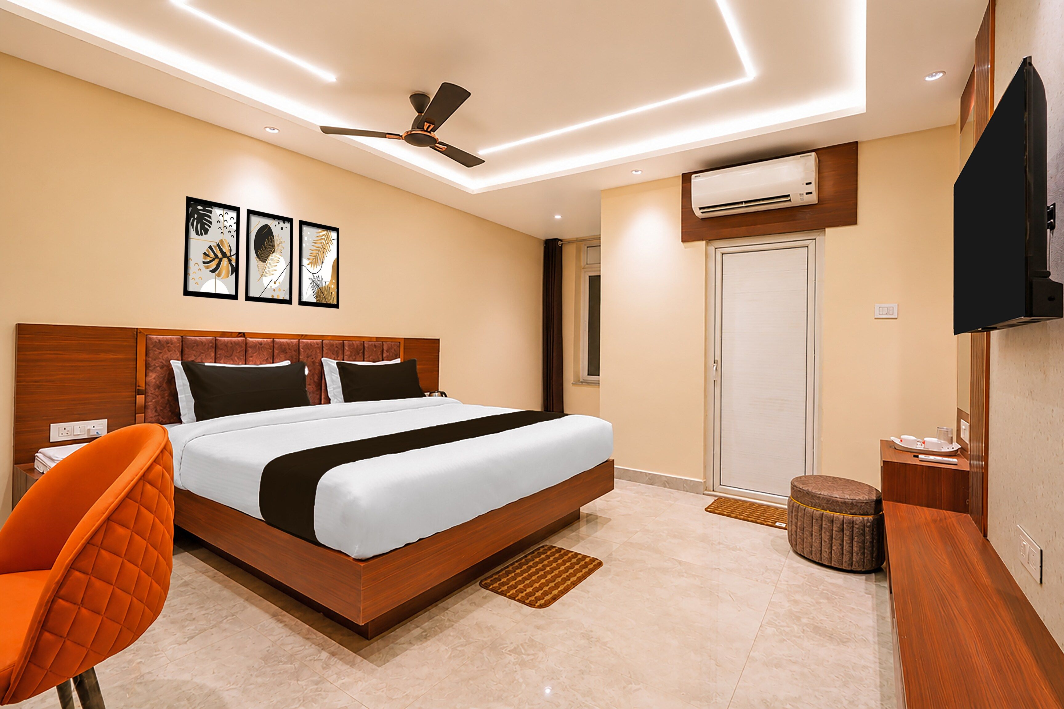 A modern hotel room with a large bed, a ceiling fan, an air conditioning unit, a TV, and artwork on the wall.
