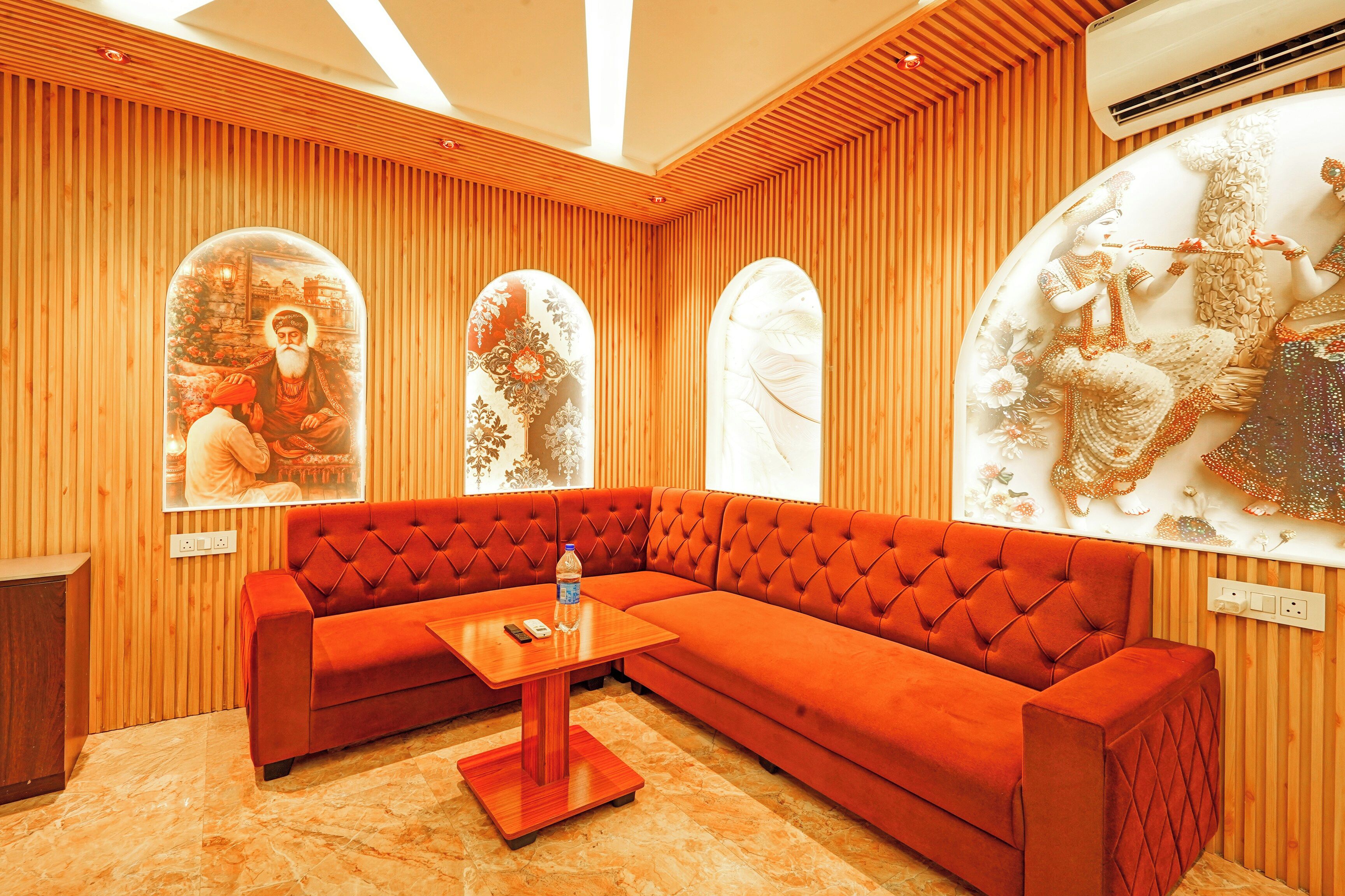 Un interior moderno con un sofá tapizado en rojo, piso de madera y arte decorativo en la pared.