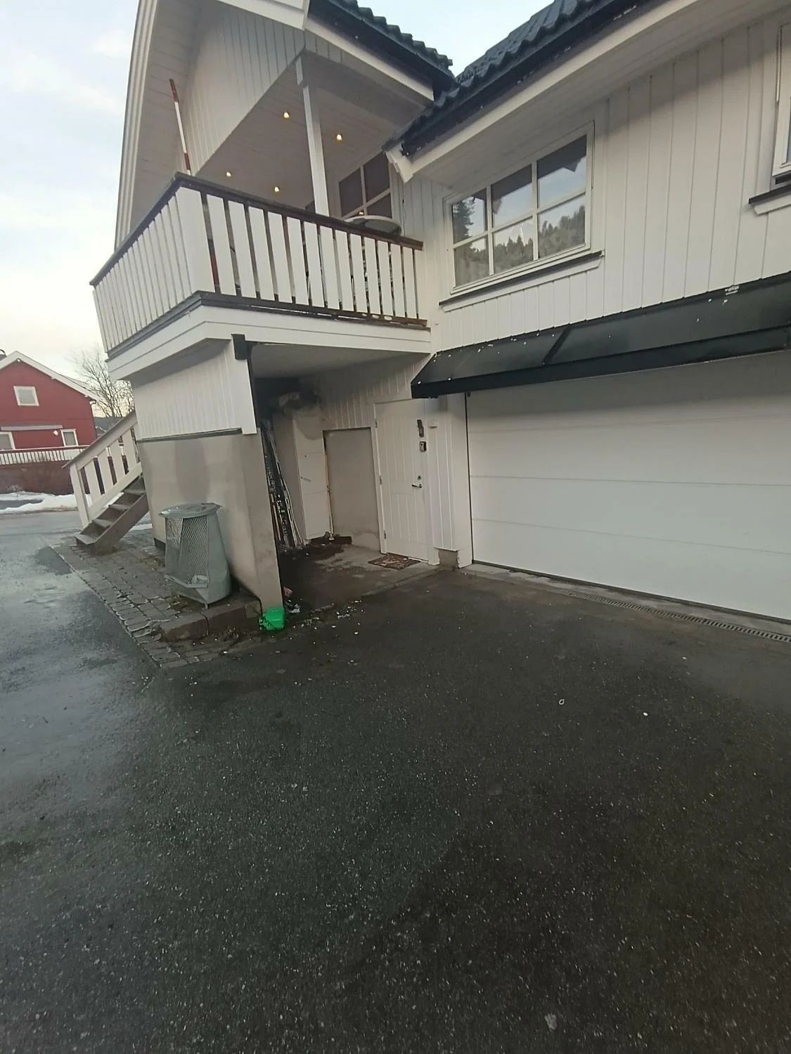 A two-story residential building with a garage, a covered porch, and a visible driveway.