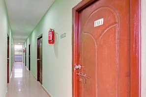 Un pasillo con puertas, un extintor y un letrero que indica una salida.