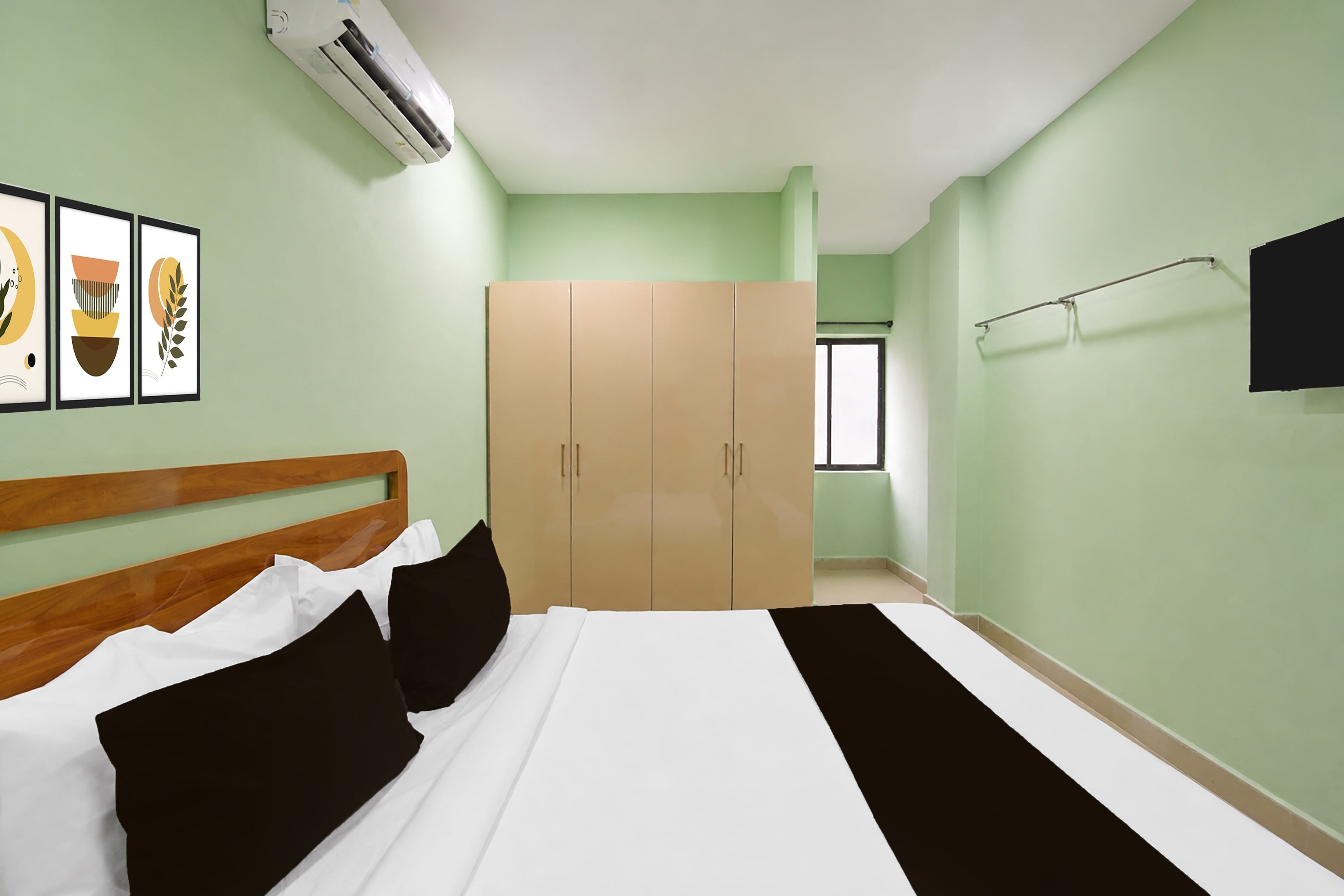 Un dormitorio con cama, armario, televisor de pantalla plana y cuadros en la pared.